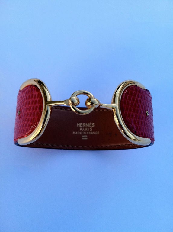 Fine & rare Hermes gold & reptile skin 'bit' cuff bracelet. Authentic signed item with French hallmarks for 18K. Red lizard skin exterior with mounted gold ends & center locking clasp.