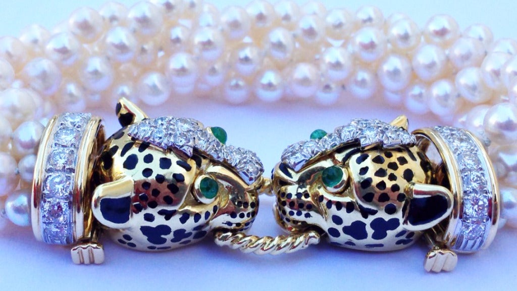 A exquisite David Webb torsade bracelet. Six strand pearl item with a yellow gold double leopard theme clasp. Black lacquer, diamonds (approx. 4.25tcw F-G VS) and emeralds (approx. .40 tcw) are added to great effect. Original signature box intact