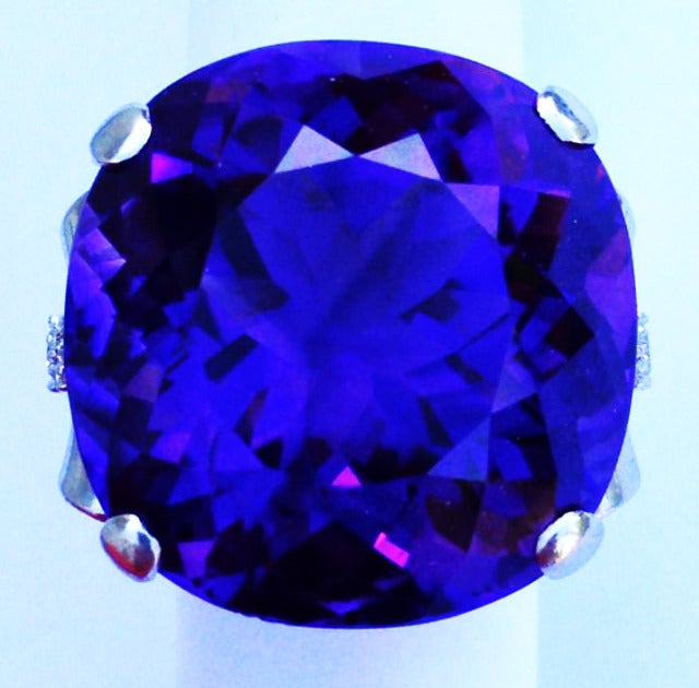 A impressive retro amethyst cocktail ring. A deep and vibrant briolette round cut amethyst (approx. 50ctw) sits atop a sculpted platinum setting with diamond accents on either side. Ring size 5.5