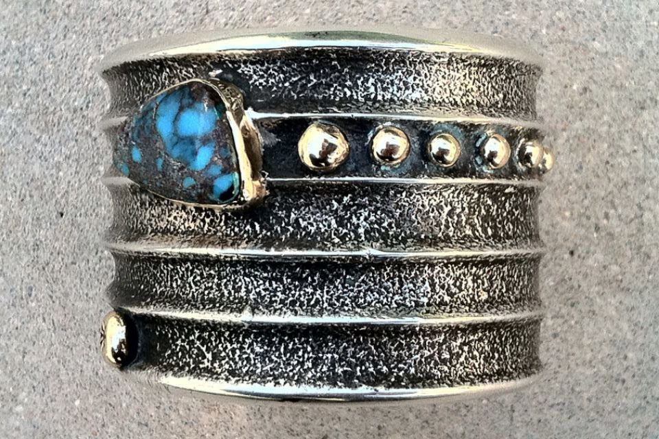 A rare man's Charles Loloma tufa cast cuff bracelet. Outstanding large sterling silver item features 14K yellow gold details and matching gold bezel set gem grade turquoise stones. An early large mans item rarely seen today.