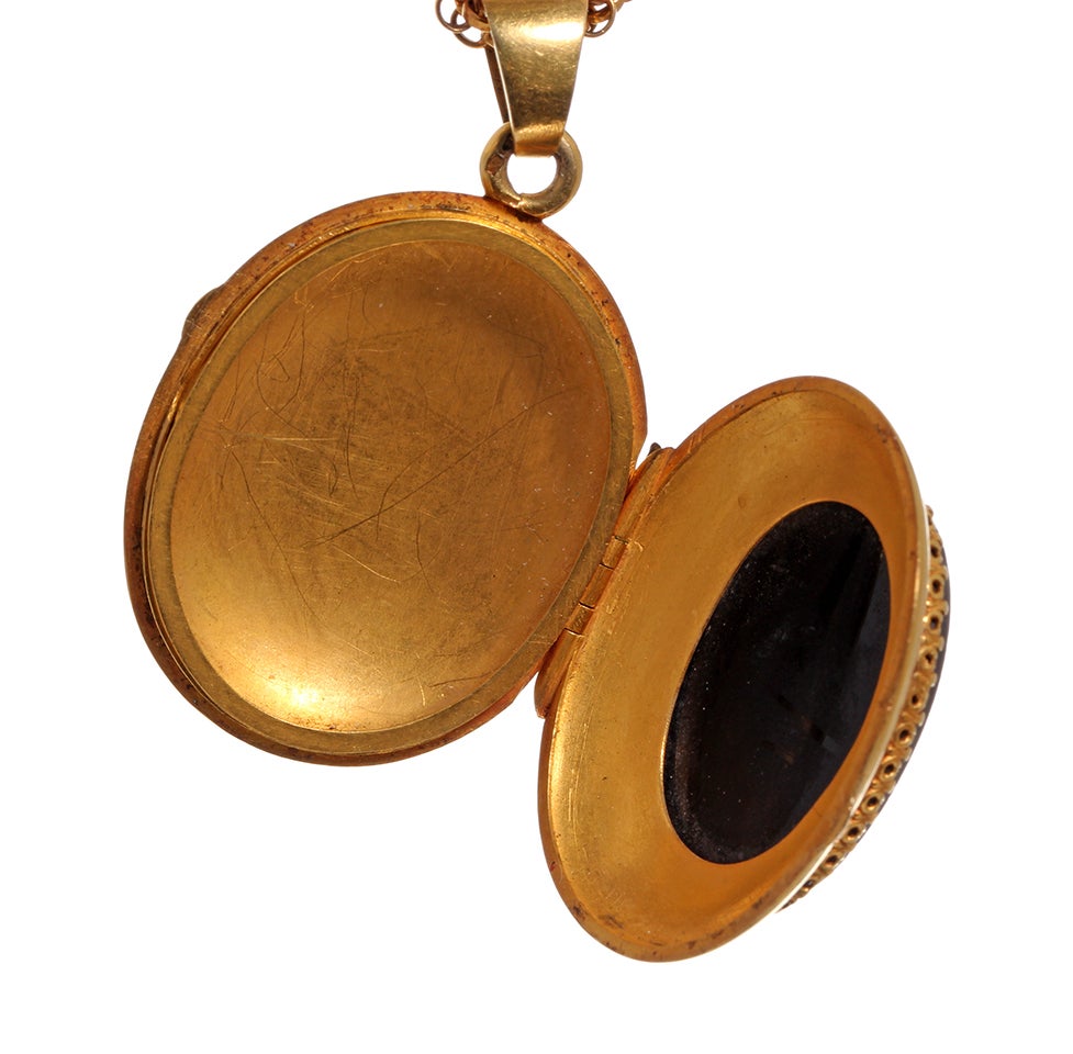 Unusual Carved hard stone 'Man in the Moon' cameo locket. Mid 19th Century French hallmarks in 18k gold. Locket is hanging on a long Victorian era gilded chain. Worn doubled, full length measures 58 inches. Locket measures 1.25