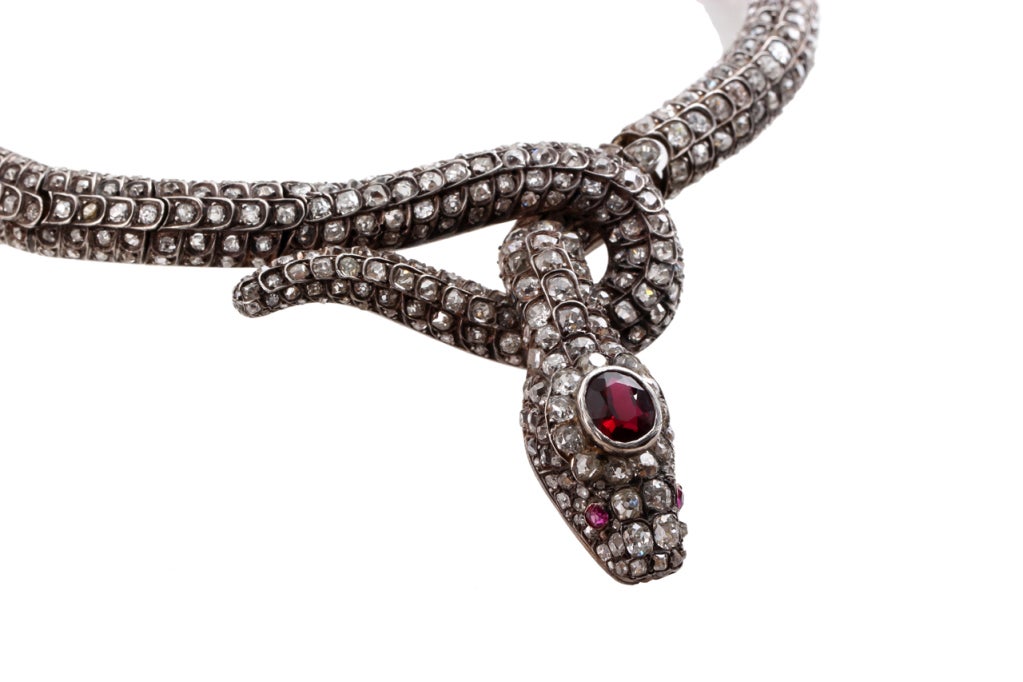 Superb French Napoleon Third Period Diamond Snake Necklace
This stunning snake necklace features old mine cut diamonds, ruby eyes, and a spinel at top of head. Most likely the original stone on head was replaced with spinel. Silver on gold. Push