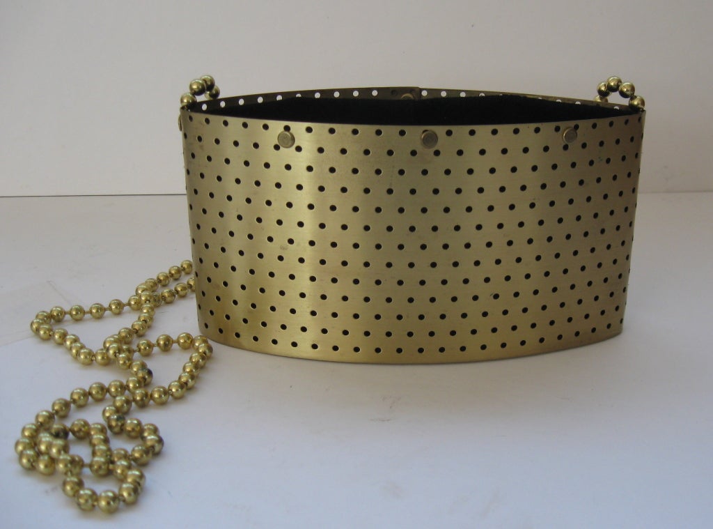 Gold colored perforated metal shoulder bag by Wendy Stevens.  Oval in shape, with a velveteen drawstring 