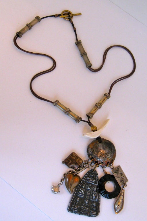 African inspired pendant necklace, featuring center medallion with six hanging charms.  Silk cord has four silver 