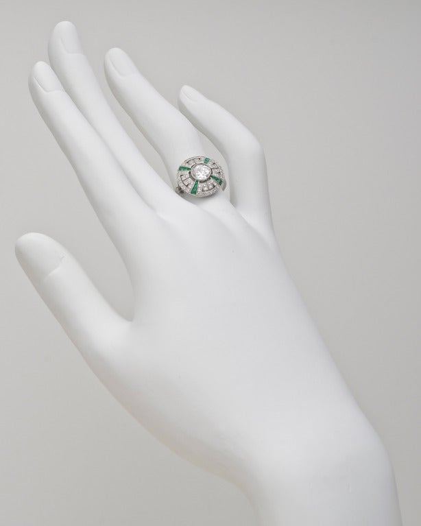 Diamond and emerald Deco-style dress ring, centering on a larger round brilliant cut diamond weighing approximately 0.65 carats (F-G color/VVS1-VVS2 clarity), with a single-cut round diamond surround composed of 56 near-colorless diamonds weighing