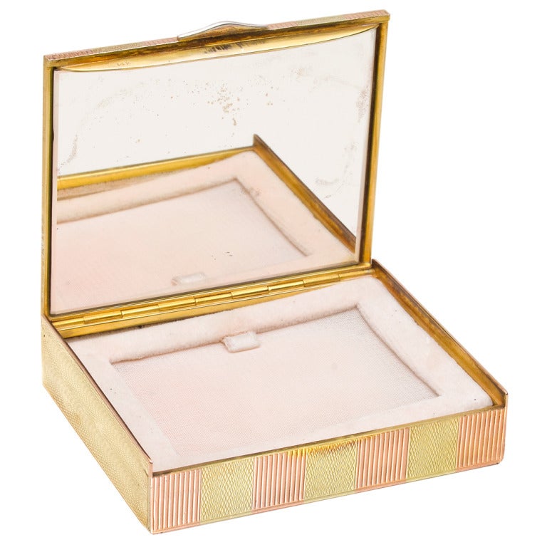 Rectangular-shaped powder case, designed with stripes in engine-turned 14k pink gold and 14k wave-patterned yellow gold, the thumb-piece set with rose-cut diamonds, opening to reveal a mirror and puff/screen. 2.9