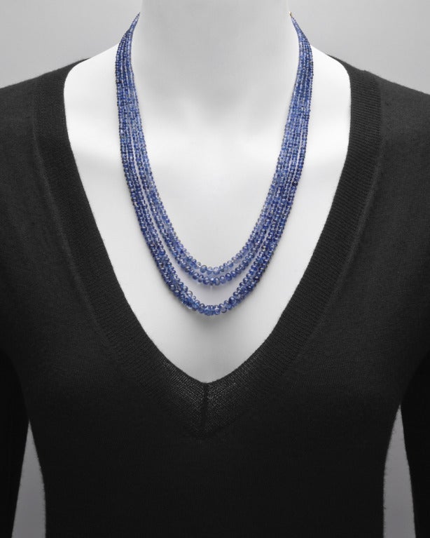 4-strand light-colored blue sapphire bead necklace, the sapphires weighing approximately 337 total carats, with an 18k yellow gold hook clasp and chain to adjust length, suspending a sapphire bead tassel with foliate-style cap. 18