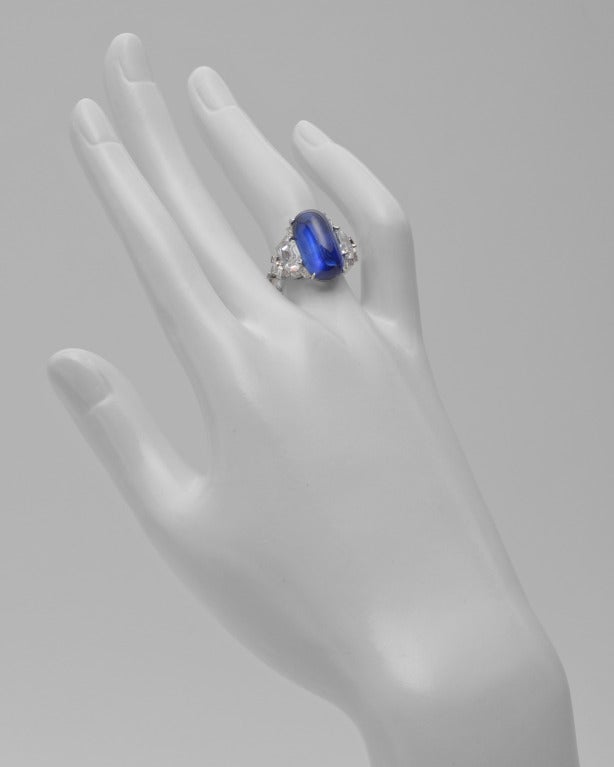 Burmese sapphire and diamond ring, centering on an elongated oval-shaped cabochon-cut sapphire weighing 10.81 carats, in a fancy platinum mounting set with two larger shield-cut diamonds weighing 1.69 total carats and smaller kite-shaped,