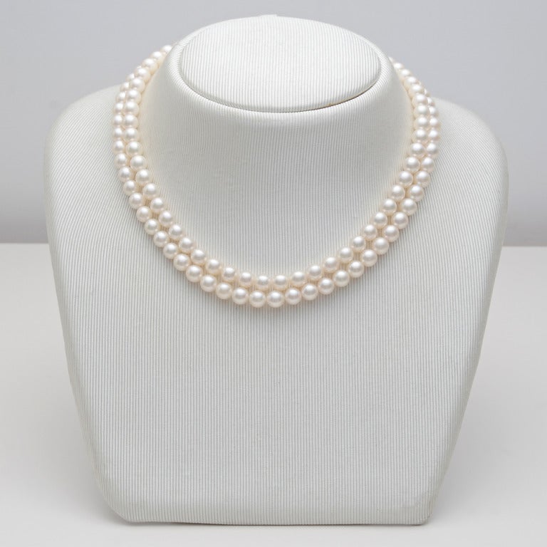 Two-strand cultured pearl necklace with a chevron-shaped, textured 18k yellow and white gold clasp, the clasp accented by small circular-cut diamonds, numbered 14069, signed Buccellati. 16