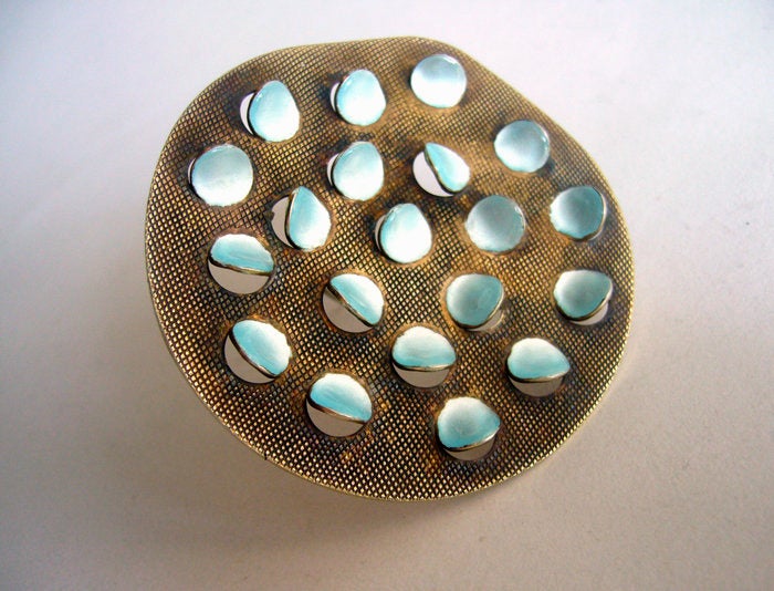 A sterling silver brooch with punched out enamelled 'scales' created by Norwegian designer, enamelist and jeweler, Grete Prytz Kittelsen. Brooch is made of sterling silver with a gold wash and pearlescent baby blue enamel.  It measures 2 1/2