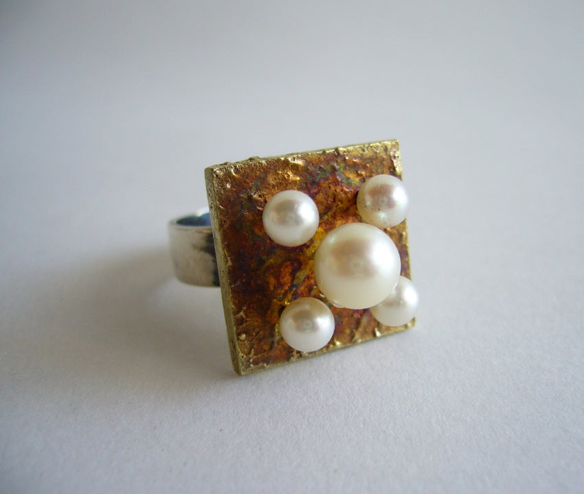 A rare pearl and sterling silver ring designed by Hans Hansen of Denmark.  Ring features a textured sterling silver gold washed plaque with five natural pearls atop sterling rods.  Ring has great depth and craftsmanship.  Signed HaH, Denmark, 925 S