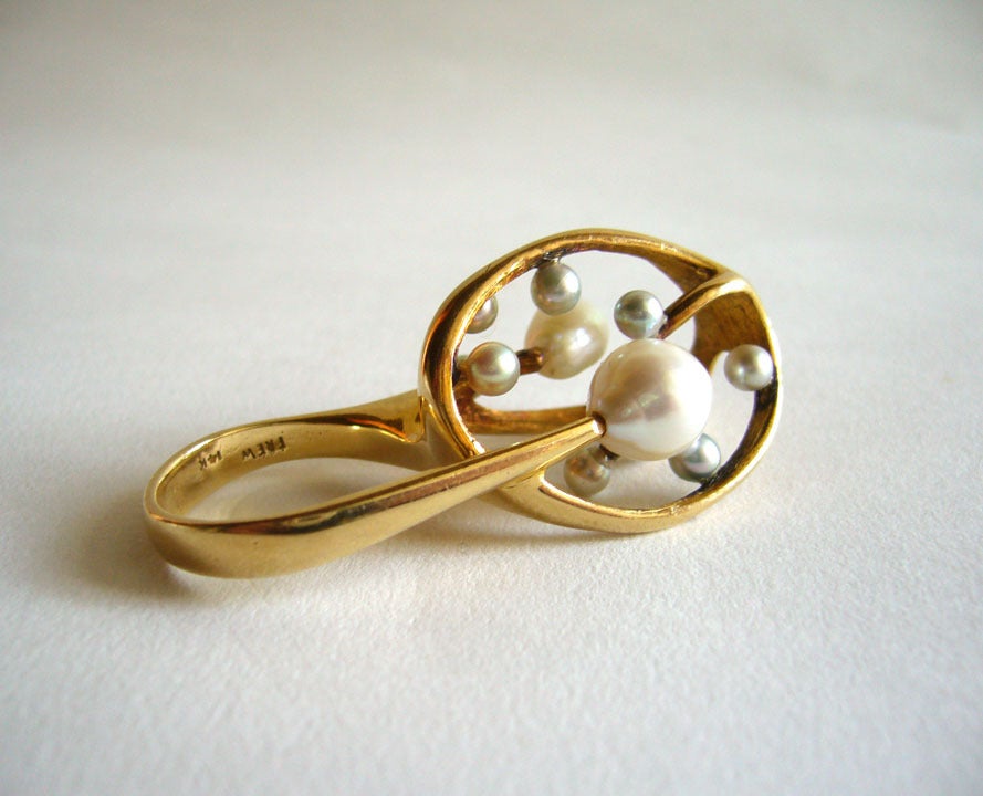 A stunning 14k gold and pearl ring designed and created by J. Arnold Frew of Arcadia, California.  Ring is comprised of eleven white and grey pearls set within a 14k gold upright web of gold.  The top of the ring stands 1 1/4