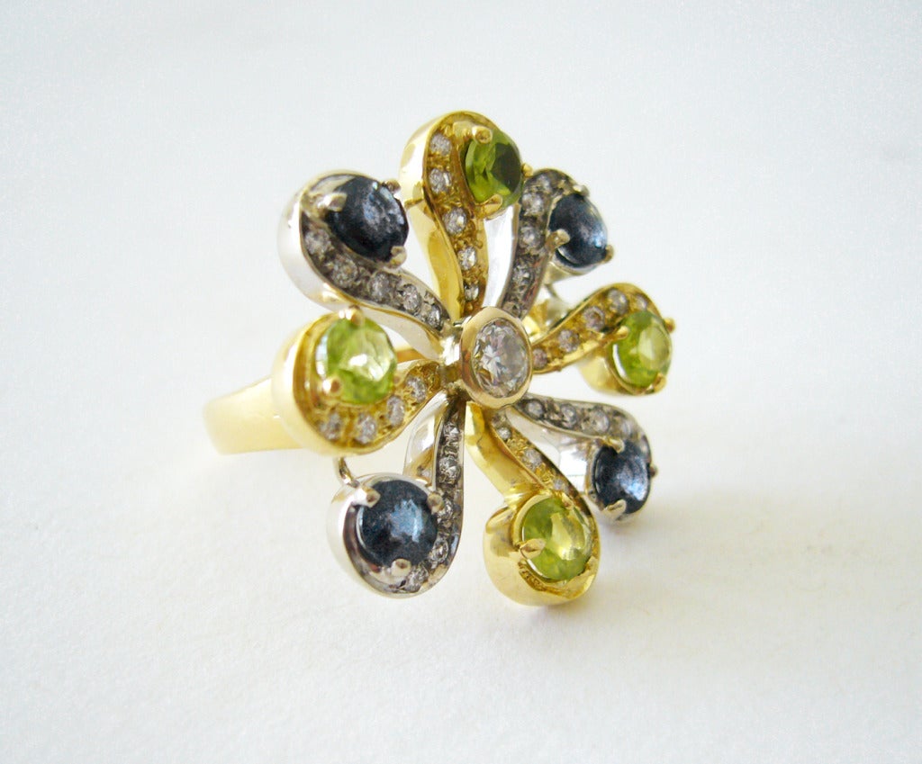 A 1970's 18k gold, diamond, blue sapphire and peridot ring comprised in a pinwheel design.  The center diamond, peridot and blue sapphires measure approximately .50 carats each while the rest of the diamonds are 1 point each.  A finger size 6 and