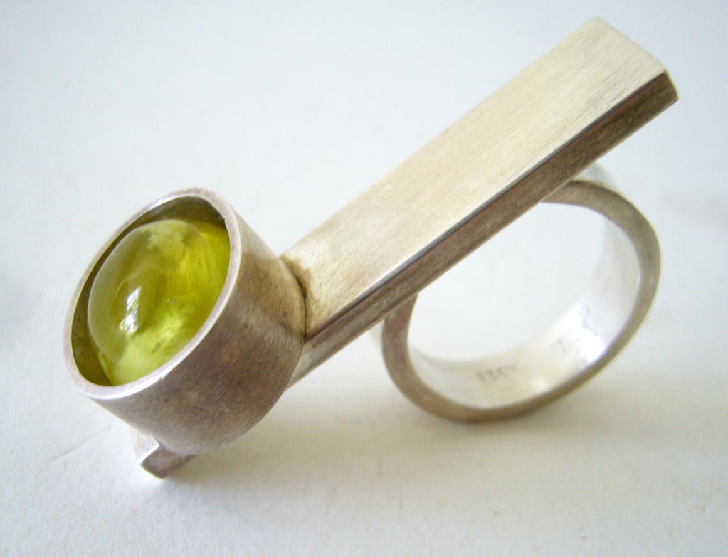 A sterling silver and Australian prehnite cabochon flat bar ring which covers two fingers, created by Heidi Abrahamson of Phoenix, Arizona.  Ring is a finger size 8 and signed Heidi, 925.  27.3 grams.  In very good condition.

Ring is featured in