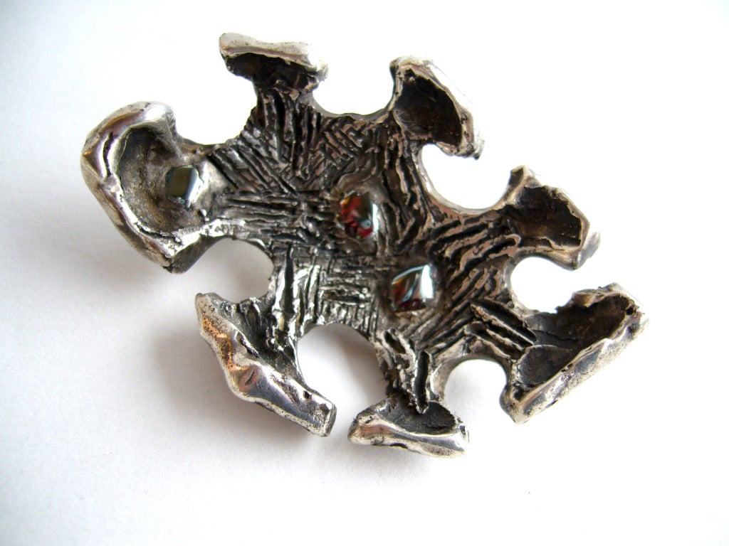 A cast, solid sterling silver and garnet brooch created by Robert Trout of Southern California.  Trout is a well known in the California craft world as a woodworker, jeweler and furniture maker and who taught at Long Beach State.  Brooch measures 2