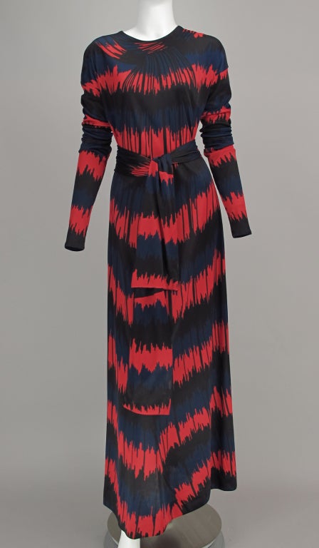 Roberta di Camerino, 1977 datiert, rotes, blaues und schwarzes Maxikleid aus Seidenstrick mit optischem Druck. Kleid zum Überziehen mit Juwelenausschnitt, extra langen Ärmeln mit jeweils drei horizontalen Nähten. A-Linien-Kleid mit selbstbindendem