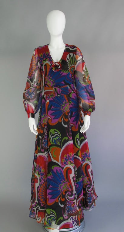Gorgeous silk gazar in brilliant colour and bold pattern…Oscar de la Renta gown from the late 1960s…fitted bodice with deep V neckline with self floral accent…full sheer long sleeves with band cuffs that close with covered snaps…bias cut skirt