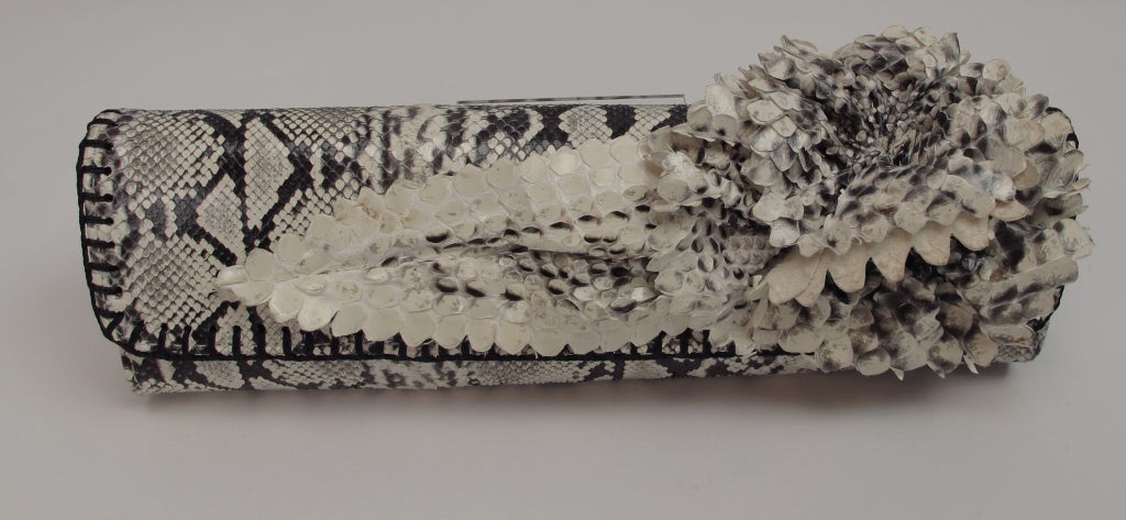 Black and white snakeskin clutch with floral snakeskin applique…structured long oval bag can be carried as a clutch or use hidden shoulder strap…10 ½” x 2” deep...Fatto a mano by Carlos Falchi.