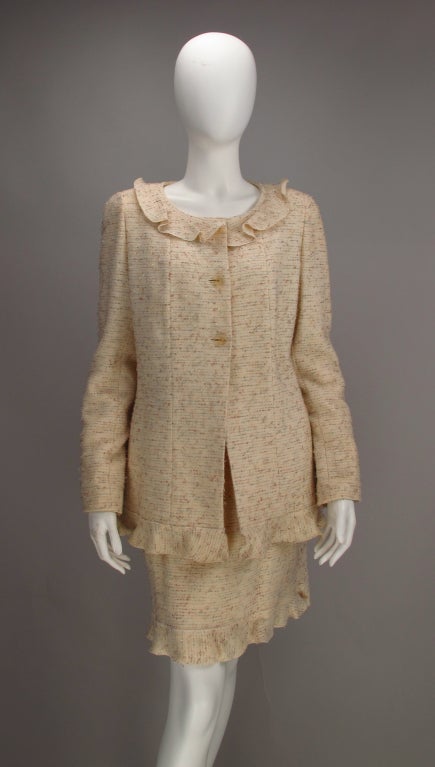 Chanel ruffle trimmed tweed suit.  Cream tweed with flecks of cocoa,cream and lavender.  ruffle edge trimming at collar, jacket & skirt hems.  Long jacket has princess seams, ruffle hem and collar, with on seam pockets. Fitted yoke waist skirt, with