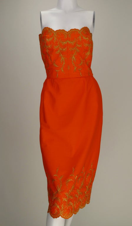 That certain shade of orange, well known along the Mediterranean from Italy to France...A strapless summer dress in polished cotton embroidered in gold metallic thread...fitted strapless bodice, fitted skirt has back kick pleat...dress closes at