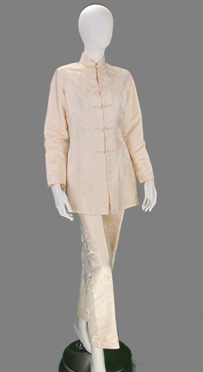 Shanghai Tang-Imperial Tailors, two piece Asian inspired women’s trouser suit in figured ivory silk…Fitted Mandarin style jacket has deep side vents, Long sleeves and closes at front with narrow cord frogs, fully lined in ivory crepe…High waist