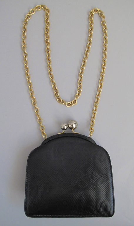 With a very Mod vibe...black lizard shoulder bag...gold chain handle...double silver ball closure with gold attachments...lined in black faille...two open compartments inside.