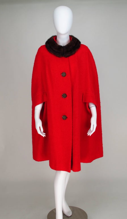The perfect winter garment...The cape, if it's very cold you can wear it over a coat, if it's not so cold throw this on over a cashmere sweater and be chic...From the 1960s a red wool boucle cape with mink fur collar...button front cape has flap