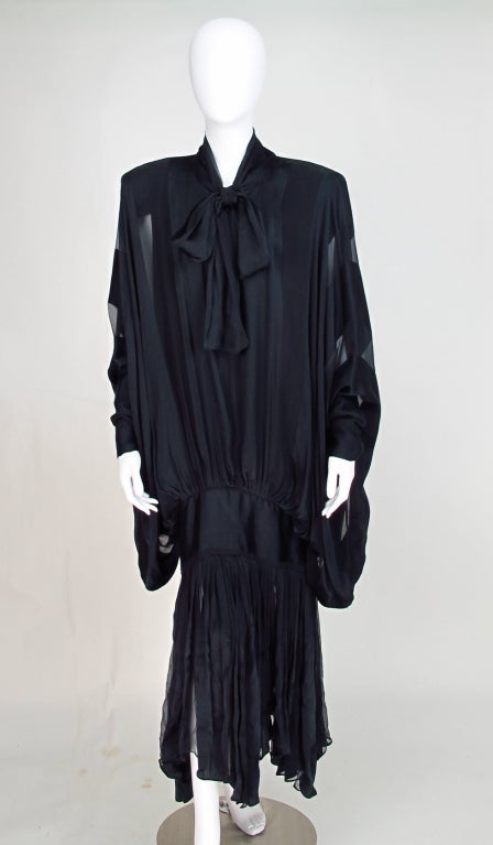 All the design drama you expect from Norma Kamali can be found in this sheer draped dress...1980s OMO...Black/blue silky fabric drapes and flows...pull on dress has long ties at the neck with a deep opening below...Huge bat wing sleeves are