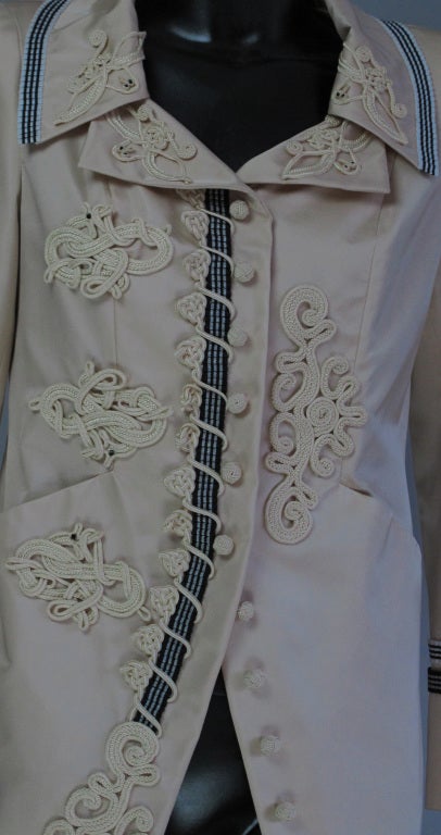Cream faille jacket…scoop neckline…fitted through the waist…four working  front pockets…two chest flap with gold flower buttons…two banded hip pockets…short belt back with two gold flower buttons…long sleeves with 3 gold flower buttons at each