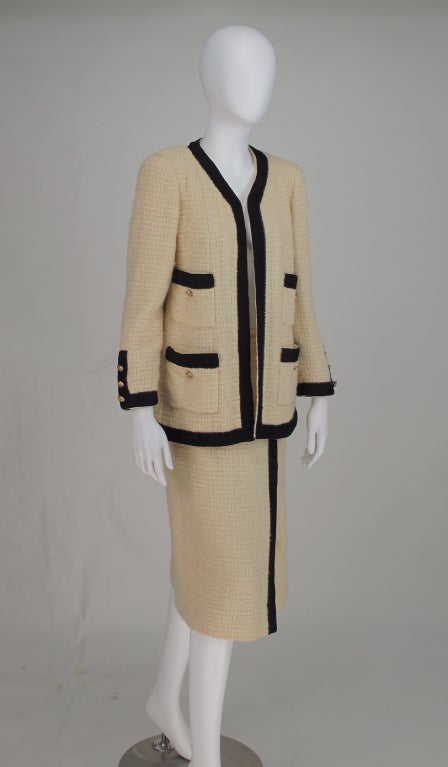 The iconic Chanel suit in buttery cream open weave wool with wide black braid, from the early 1980s designed by Karl Lagerfeld...I love this jacket with skinny leather pants...Hip length open front jacket has four patch pockets with logo