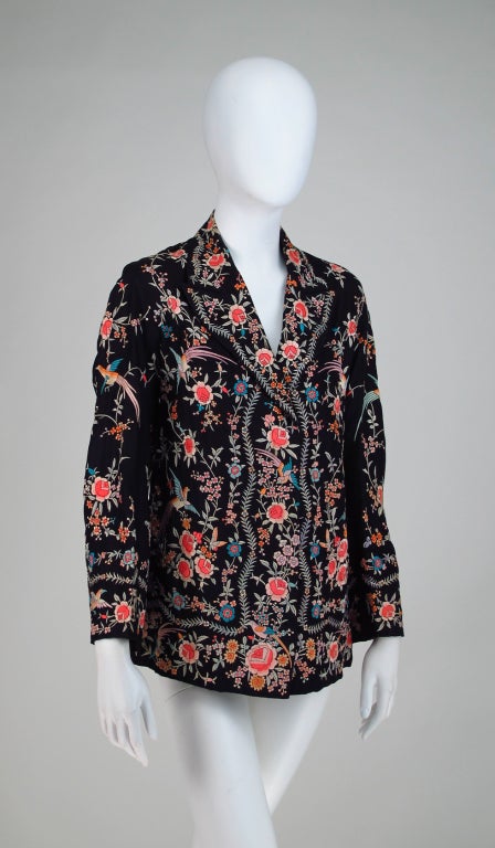 Embroidered black silk evening jacket from the 1920s...Banded hip length style with narrow shoulders, long sleeves and hook front closure, lined in black silk...Colourful satin stitch is done in vivid silk floss and has birds and flowers scattered