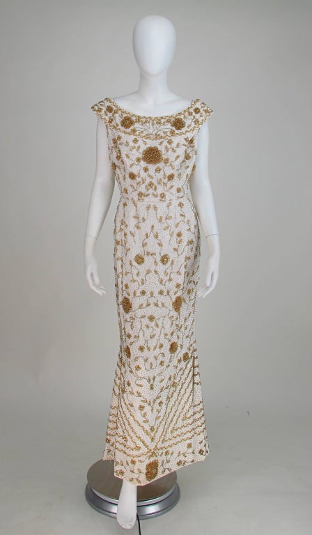 A gown that invokes screen goddesses from days gone by when women were curvaceous and proud to be so! A dress for serious evenings out! Mignon ivory silk gown from the late 1950s/early 60s heavily beaded in gold glass beads...Wide low neckline that