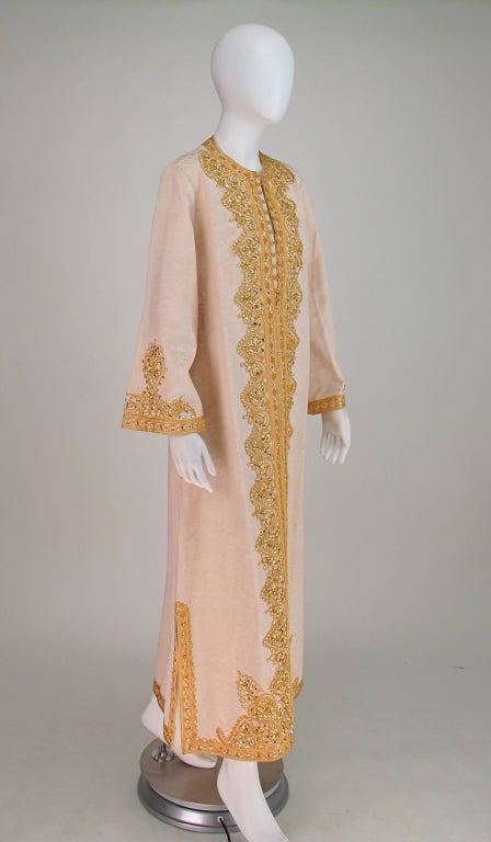 For at home entertaining...A gorgeous caftan from the 1960s, in champagne silk faille, heavily embroidered with sequins and gold cording...Pull on style with cord button and loops at the front neck line...Unlined...In very good wearable condition,