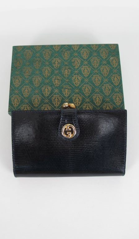The perfect gift for the vintage Gucci lover on your list! New in the box Gucci black lizard clutch wallet from the 1970s...Features black calf lining with lizard trims, gold Gucci logo snap, a kisslock change purse, large bill compartment, inside