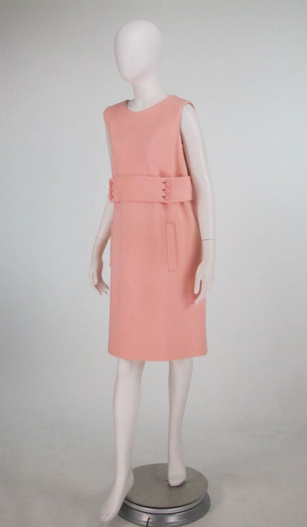 Norman Norell, 1960s knit jersey sheath dress...Sleeveless dress buttons at the back with bound button holes and shaped pink buttons...There is a wide self band at the waist with matching buttons at the front, on seam banded front pockets...Dress is