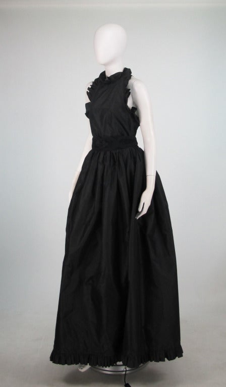 Darkly romantic...Oscar de la Renta black silk halter neck gown from the 1960s (we originally had this mislabeled as 1990s) with the original black suede & cord belt...Bodice and hem are trimmed in a narrow silk ruffle...Dress ties at the neck