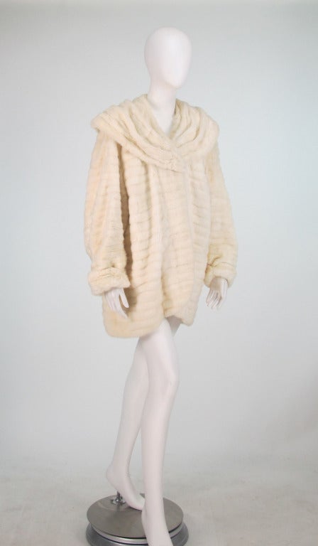 Cocoon wrap coat in ermine fur from the 1930s...Coat has full sleeves that narrow to turn back cuffs, coat dips at the hem back, attached shawl collar...Fully lined in crepe...Has the original interior arm straps so it can be worn without using the