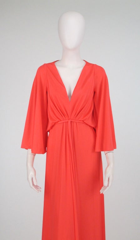 Estevez plunge front gown from the 1970s...Silky coral jersey with angel sleeves, deep plunge neckline, gathered at under bust band...Draped bodice back is open, there is an under bodice...Closes at the back with a zipper &