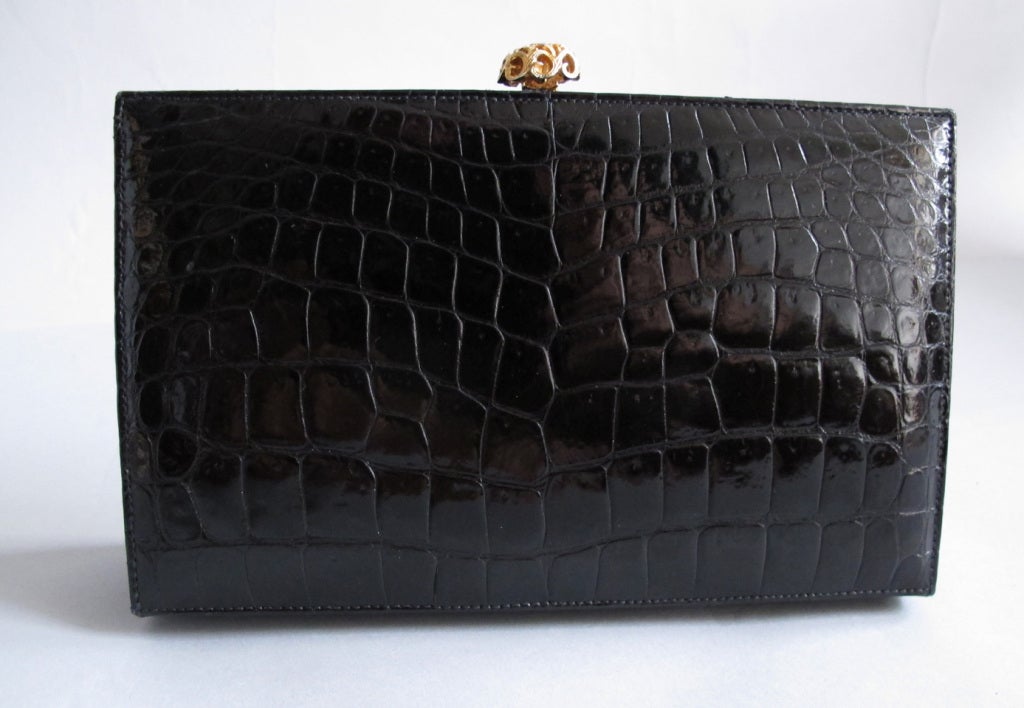 From Art Bag New York, black crocodile frame clutch bag…outside front, back and bottom are crocodile skin. Sides and top frame are black leather…bag is lined in black leather. Inside features two open compartments and one zipper compartment…closes