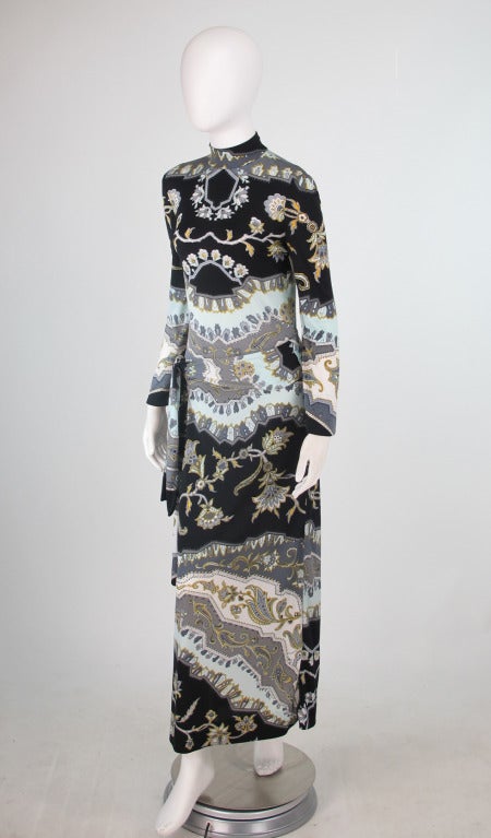 Leonard, Paris long bell sleeve column gown, with hip wrap self belt...Bold  print in in black, blue, gold, gray with white on silky jersey...High banded neckline, long bell shape sleeves, bodice is attached to skirt at the hip line...Sleek modern