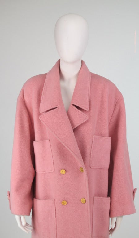 1980s Chanel classic chesterfield style over coat in ballet pink wool...Double breasted coat with notched shawl collar, four patch pockets at the front with Chanel logo buttons in gold...Belt back with gold logo button detail...Deep center back hem