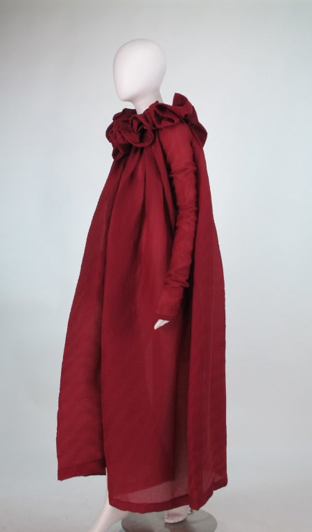 1990s Romeo Gigli ethereal pinch pleated coat...Garnet red, button front coat is of sheer horizontal fabric that is pinch pleated but flowing...Portrait, stand away, ruched & ruffled collar...The armholes are cut high and narrow and the sleeves are