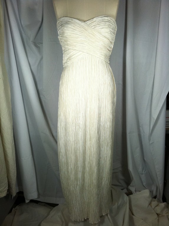 Vintage cream mini-pleated gown originally from I.Magnin.  Clean, elegant lines with criss-cross bust and spaghetti straps. Side zipper.<br />
Please note that all sales are final. No returns or exchanges. Please call us with any questions or for