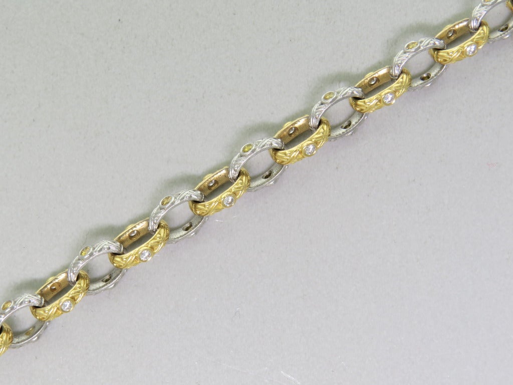 18-karat yellow gold, platinum and diamond Carved chain bracelet. Features twenty-two white diamonds totaling 0.44 carat and thirty-one natural fancy color diamonds totaling 0.62 carat. Total diamond weight 1.06ctw. 6 7/8