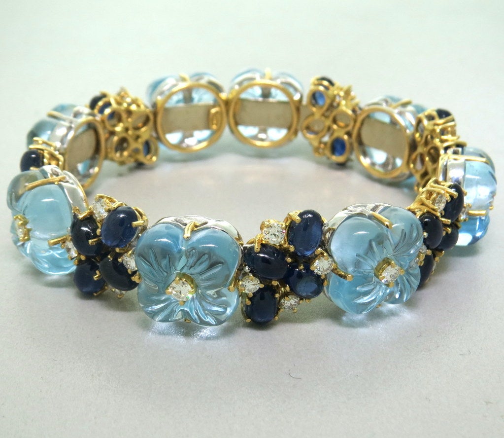 18k yellow gold bracelet with carved light blue topaz flowers,approx. 8.5-9ctw sapphire cabochons and 1.50ctw diamonds. Bracelet will fit up to 7