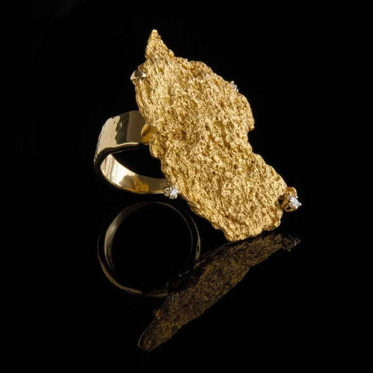 A dramatic, statement ring featuring a flat nugget of raw 22/24K (depending on natural impurities) placer gold edged with three diamonds (total 0.14ct) on an 18K gold band. The nugget has been claw-set allowing it to be removed without damage if