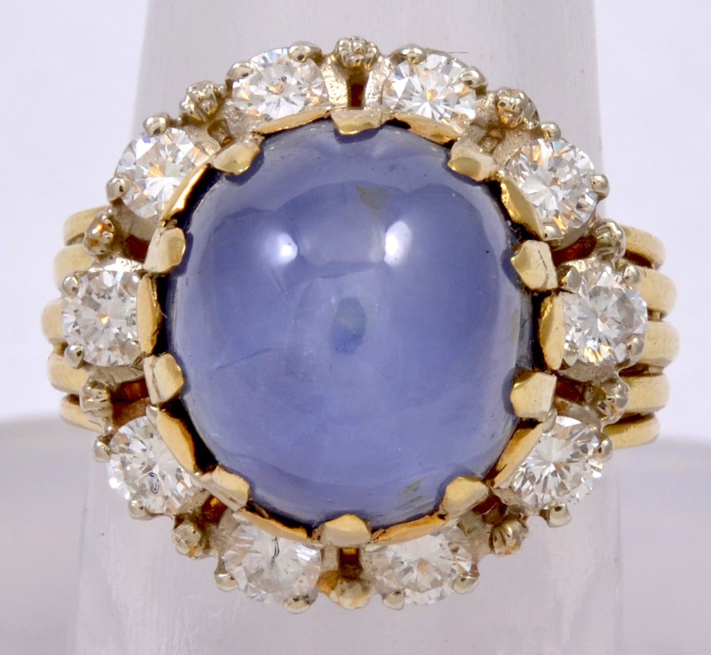 Gold, Diamond and Sapphire Ring.  This ring is composed of a Cabochon Star Sapphire surmounting a circle of ten round brilliant diamonds  set in yellow 18 karat gold. 10 Diamonds approximately total weight 1.0 Cts.  Ring is size 6 (NOTE: Can be