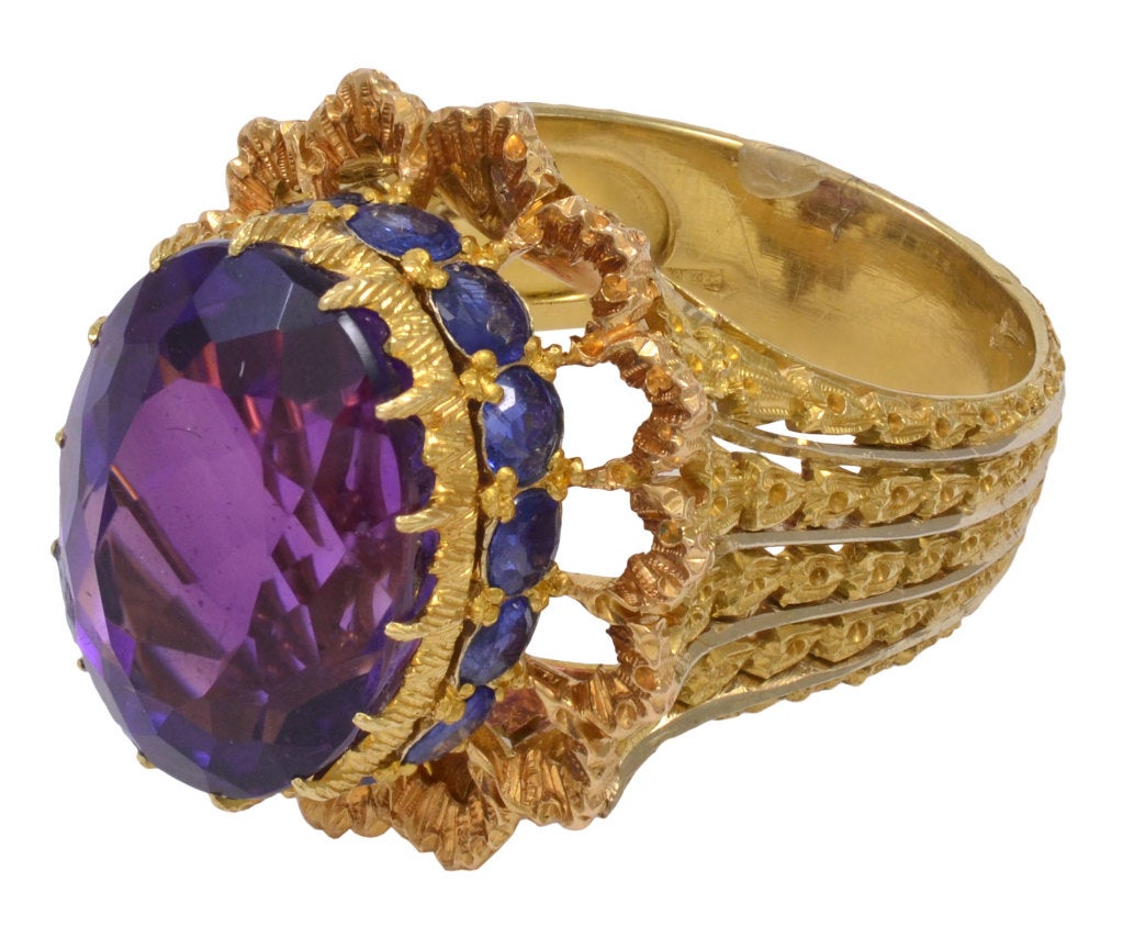 BUCELLATI Gold, Amethyst and Sapphire Ring and Earring Set.  The 18 karat gold ring is engraved with leaf garlands supporting a crown of composed of central oval cut amethyst surrounded by round cut sapphires set in pierced ribbon-form mounting. 