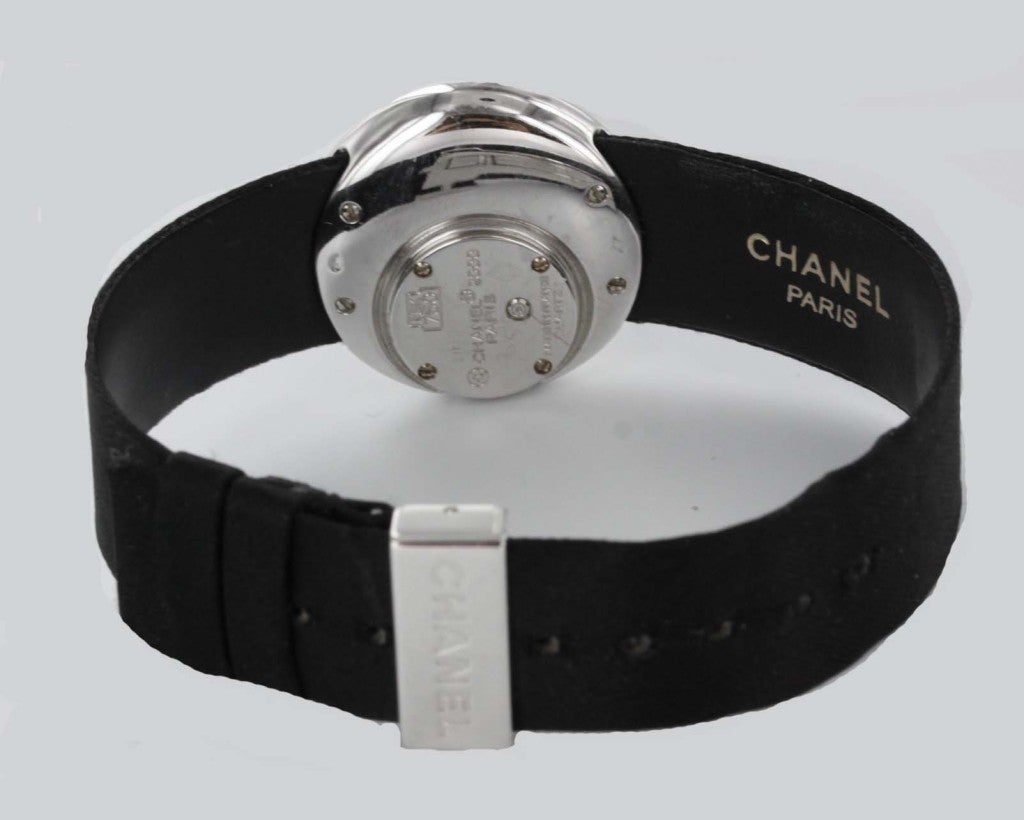 This stunning Chanel wristwatch from the '90s features an 18k white gold crescent set with glittering white diamonds, surrounding a 26mm face of black diamonds. Quartz movement, original satin Chanel strap and deployment buckle.