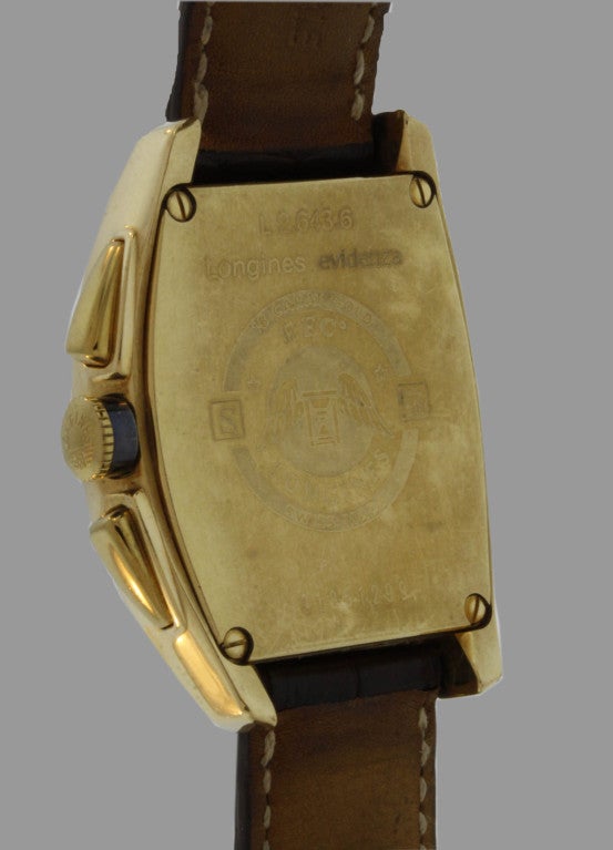 Classic and chic, this curved rectangular automatic Longines 18k yellow gold wristwatch features an off-white dial with black Arabic numerals, chronograph with  two registers and date. It is numbered 31851299.